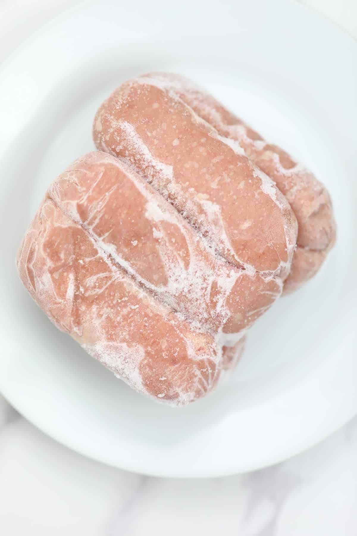 raw frozen sausages on a plate.