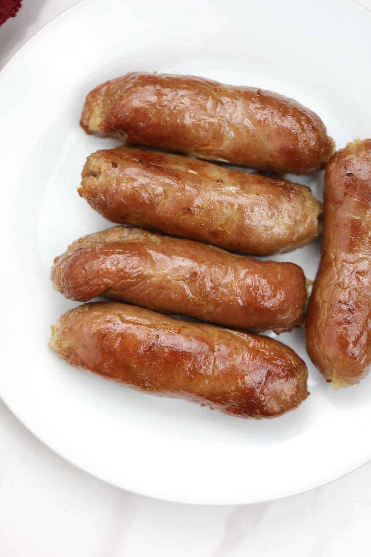 5 sausages on a white plate.